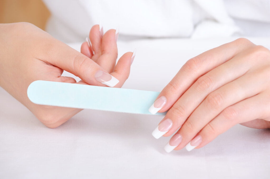 woman filing her nails after a polygel manicure 