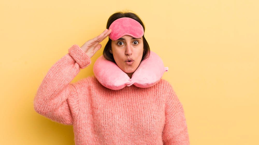 woman standing in front of a yellow background wearing a heated eye mask