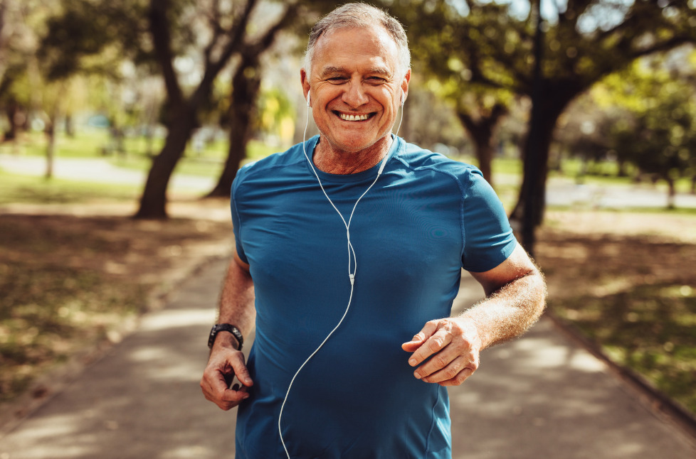Homme d'âge souriant en train de courir après une séance de ceinture vibrante dans une optique de perte de poids
