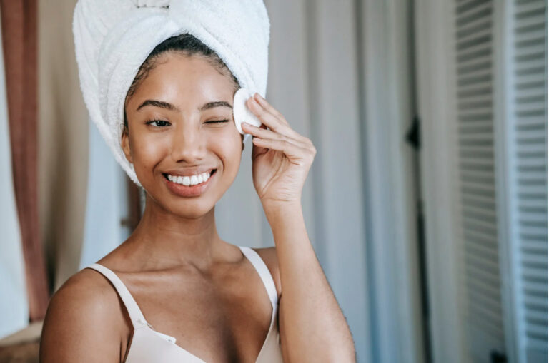 Os segredos de uma rotina eficaz de cuidados com a pele: uma mulher que remove a maquiagem com um sorriso