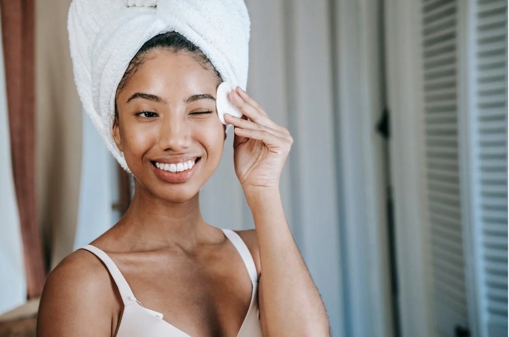 Les secrets d'une routine de soin de visage efficace : Femme qui se démaquille avec le sourire